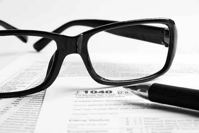 Picture of glasses on IRS form to accompany article about IRS tool to use social media to catch tax cheats